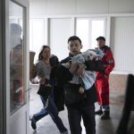 
              FILE - Marina Yatsko, left, runs behind her boyfriend Fedor carrying her 18 month-old son Kirill who was killed in shelling, as they arrive at a hospital in Mariupol, Ukraine, Friday, March 4, 2022. (AP Photo/Evgeniy Maloletka, File)
            