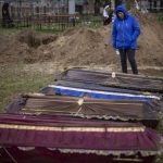 
              CAPTION CORRECTS LOCATION - Ira Slepchenko, 54, cries next to coffins, one of them with the body of her husband Sasha Nedolezhko, 43, during an exhumation of civilians killed and buried in a mass grave in Mykulychi, Ukraine on Sunday, April 17, 2022. All four bodies in the village grave were killed on the same street, on the same day. Their temporary caskets were together in a grave. On Sunday, two weeks after the soldiers disappeared, volunteers dug them up one by one to be taken to a morgue for investigation. (AP Photo/Emilio Morenatti)
            