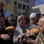 
              A volunteer, right, distributes humanitarian aid in a yard of a school in Chernihiv, Ukraine, Thursday, April 7, 2022. (AP Photo/Evgeniy Maloletka)
            