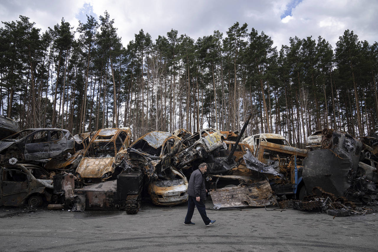 A man walks past a storage place for burned armed vehicles and cars, in the outskirts of Kyiv, Ukra...