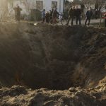 
              People look at a crater of an explosion in a village of Horodnya, Chernihiv region, Ukraine, Thursday, April 14, 2022. The fluid nature of the conflict, which has seen fighting shift away from areas around the capital and heavily toward Ukraine's east, has made the task of reaching hungry Ukrainians especially difficult. (AP Photo/George Ivanchenko)
            