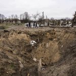 
              People walk past a crater from an explosion in Chernihiv, Ukraine, Wednesday, April 13, 2022. (AP Photo/Evgeniy Maloletka)
            