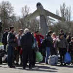 
              People wait to board a bus during their evacuation, with a Soviet MiG-17 fighter jet monument right in the background, in Kramatorsk, Ukraine, Saturday, April 9, 2022. After the bombing of the train station Friday, resident are continuing their attempts to leave the city on buses and other transports. (AP Photo/Andriy Andriyenko)(AP Photo/Andriy Andriyenko)
            