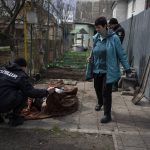 
              A policeman examinares the corpse of a man killed during the war with Russia in Bucha, in the outskirts of Kyiv, Ukraine, Monday, April 11, 2022. (AP Photo/Rodrigo Abd)
            