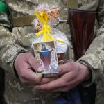 
              A Ukrainian soldier holds an Easter cake and an icon during a blessing ceremony on Easter eve at a military position outside Kyiv, Ukraine, Saturday, Apr. 23, 2022 (AP Photo/Efrem Lukatsky)
            