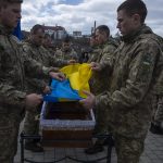 
              Soldiers place the Ukrainian flag on the coffin of 41-year-old soldier Simakov Oleksandr, during his funeral ceremony, after after he was killed in action, at the Lychakiv cemetery, in Lviv, western Ukraine, Monday, April 4, 2022. (AP Photo/Nariman El-Mofty)
            