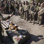 
              A military Orthodox priest blesses traditional food during the Easter celebration at the frontline position of 128 brigade of Ukrainian army near Zaporizhzhia, Ukraine, Sunday, April 24, 2022. (AP Photo/Andriy Dubchak)
            