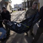 
              Volunteers carry the body of a man killed during the war to a refrigerated container in Bucha, in the outskirts of Kyiv, Ukraine, Thursday April 14, 2022. (AP Photo/Rodrigo Abd)
            