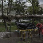 
              Emergency workers remove the body of a man killed during a Russian bombardment in Kharkiv, Ukraine, Wednesday, April 27, 2022. (AP Photo/Felipe Dana)
            