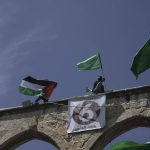 
              Protesters wave the Palestinian and Hamas flags after Friday prayers during the Muslim holy month of Ramadan, hours after Israeli police clashed with protesters at the Al Aqsa Mosque compound, in Jerusalem's Old City, Friday, April 22, 2022. (AP Photo/Mahmoud Illean)
            