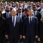 
              Israeli Prime Minister Naftali Bennett and his wife Galit stand still together with Israeli President Isaac Herzog and his wife Michal during the ceremony marking Holocaust Remembrance Day at Warsaw Ghetto Square at the Yad Vashem memorial in Jerusalem, Thursday, April 28, 2022. (Amir Cohen/Pool Photo via AP)
            
