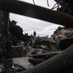 
              A local man stands atop of destroyed Russian armoured vehicles in Bucha, Ukraine, Tuesday, April 19, 2022. (AP Photo/Evgeniy Maloletka)
            