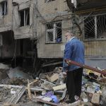 
              A man stands next to an apartment building damaged by shelling in Kharkiv, Ukraine, Sunday, April 10, 2022. (AP Photo/Andrew Marienko)
            