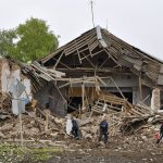 
              Men walk past a damaged building after Russian shelling in Soledar, Donetsk region, Ukraine, Wednesday, May 18, 2022. (AP Photo/Andriy Andriyenko)
            