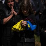
              Shufryn Lilia, 17, holding a Ukrainian flag, cries next to the coffin of her father Shufryn Andriy, 41, a Ukrainian military servicemen who as killed in the east, during his funeral in Lviv, Ukraine, Saturday, May 14, 2022. (AP Photo/Emilio Morenatti)
            