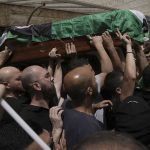 
              Mourners carry the Palestinian flag-draped coffin of slain Al Jazeera veteran journalist Shireen Abu Akleh on the way to her final resting place, in east Jerusalem, Friday, May 13, 2022. Abu Akleh, a Palestinian-American reporter who covered the Mideast conflict for more than 25 years, was shot dead Wednesday during an Israeli military raid in the West Bank town of Jenin.(AP Photo/Mahmoud Illean)
            