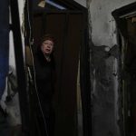 
              Klavdiya Tyshenko stands at the entrance of her home ruined by shelling in Irpin, outskirts of Kyiv, Ukraine, Tuesday, May 24, 2022. (AP Photo/Natacha Pisarenko)
            