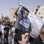 
              Mourners hold a banner depicting slain Al Jazeera veteran journalist Shireen Abu Akleh as they walk from the Old City of Jerusalem to her burial site, Friday, May 13, 2022. Abu Akleh, a Palestinian-American reporter who covered the Mideast conflict for more than 25 years, was shot dead Wednesday during an Israeli military raid in the West Bank town of Jenin.(AP Photo/Ariel Schalit)
            