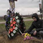 
              Yura Nechyporenko, 15, places a chocolate at the grave of his father Ruslan Nechyporenko at the cemetery in Bucha, on the outskirts of Kyiv, Ukraine, on Thursday, April 21, 2022. The teen survived an attempted killing by Russian soldiers while his father was killed, and now his family seeks justice. (AP Photo/Petros Giannakouris)
            