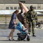 
              A woman with her child walks past a Russian soldier at an embankment of the Black Sea in Kherson, Kherson region, south Ukraine, Friday, May 20, 2022. The Kherson region has been under control of the Russian forces since the early days of the Russian military action in Ukraine. This photo was taken during a trip organized by the Russian Ministry of Defense. (AP Photo)
            