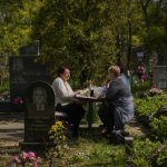 
              Vera Velakanova, left, and Lyudmila Vondarenko eat some food at the Kapustyanyy cemetery during the day that Ukrainians mark as the day of the dead, in Zaporizhzhia, Ukraine, Sunday, May 1, 2022. (AP Photo/Francisco Seco)
            