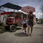 
              Danmara Triana walks home after picking up her daughter Alice from school in Cienfuegos, Cuba, Thursday, May 19, 2022. Triana's husband and son, who is Alice's father and brother, have lived in the U.S. since 2015, while she and their two daughters stayed behind. (AP Photo/Ramon Espinosa)
            