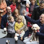 
              Australia's Prime Minister-elect Anthony Albanese, right, with his dog Toto, on his lap, takes a photo with community members while having coffee in Sydney, Sunday, May 22, 2022. Albanese has promised to rehabilitate Australia's international reputation as a climate change laggard with steeper cuts to greenhouse gas emissions. (Dean Lewins/AAP Image via AP)
            