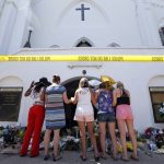 FILE - A group of women pray together at a makeshift memorial on the sidewalk in front of the Emanuel AME Church in on June 18, 2015, in Charleston, S.C.  For many Black Americans, the shooting at a supermarket on Saturday, May 14, 2022, in Buffalo, New York, has stirred up the same feelings they faced after Charleston and other attacks: the fear, the vulnerability, the worry that nothing will be done politically or otherwise to prevent the next act of targeted racial violence.    (AP Photo/Stephen B. Morton, File)