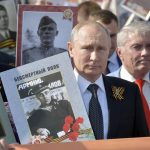 
              FILE - Russian President Vladimir Putin, center, holds a portrait of his father Vladimir Spiridonovich Putin, in front of him, as he walks among other people carrying portraits of relatives who fought in World War II, during the Immortal Regiment march through Red Square celebrating 74 years since the victory in WWII in Red Square in Moscow, Russia, Thursday, May 9, 2019. The defeat of Nazi Germany in World War II that Russia celebrates on May 9 is the country's most important holiday. This year it has special meaning amid the war in Ukraine, which the Kremlin calls a "special military operation" aimed to rid the country of alleged "neo-Nazis" — a false accusation derided by the West. (Alexei Druzhinin, Sputnik, Kremlin Pool Photo via AP, File)
            