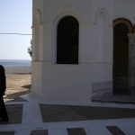 
              A Greek Orthodox priest walks in front of Agios Nikolaos church on the Aegean Sea island of Tilos, southeastern Greece, Tuesday, May 10, 2022. When deciding where to test green tech, Greek policymakers picked the remotest point on the map, tiny Tilos. Providing electricity and basic services, and even access by ferry is all a challenge for this island of just 500 year-round inhabitants. It's latest mission: Dealing with plastic. (AP Photo/Thanassis Stavrakis)
            