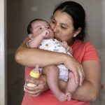 
              Yury Navas, 29, of Laurel, Md., kisses her two-month-old son, Jose Ismael Gálvez, after making him a bottle of formula with the only formula he can take without digestive issues, Enfamil Infant, from her dwindling supply of formula at their apartment in Laurel, Md., Monday, May 23, 2022. After this day's feedings she will be down to their last 12.5 ounce container of formula. Navas doesn't know why her breastmilk didn't come in for her third baby and has tried many brands of formula before finding the one kind that he could tolerate well, which she now says is practically impossible for her to find. To stretch her last can she will sometimes give the baby the water from cooking rice to sate his hunger. (AP Photo/Jacquelyn Martin)
            