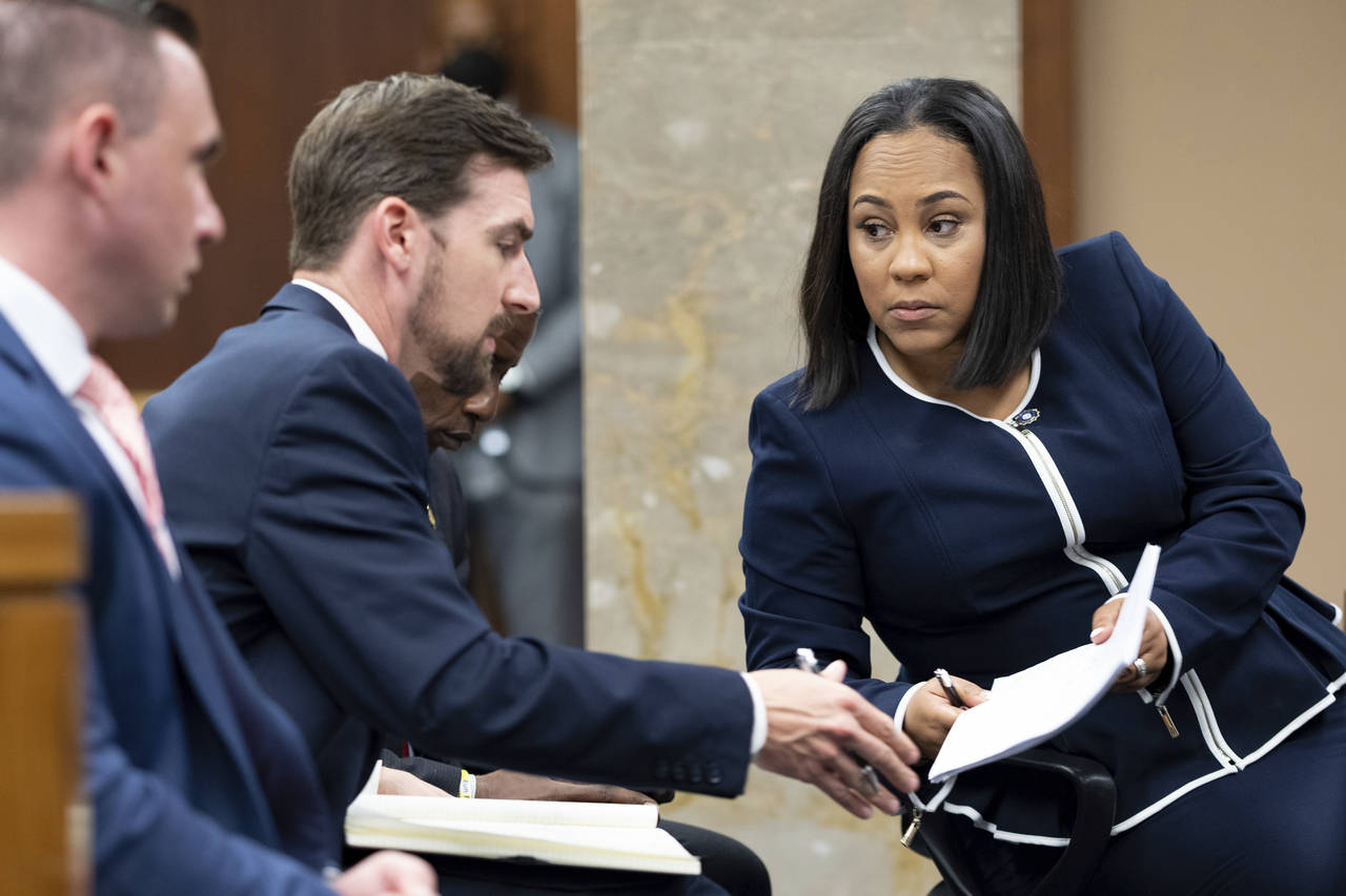 Fulton County District Attorney Fani Willis, right, talks with a member of her team during proceedi...