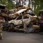 
              A territorial defence man poses for a photo next to cars destroyed during the Russian occupation in Irpin, on the outskirts of Kyiv, on Saturday, May 7, 2022. (AP Photo/Emilio Morenatti)
            