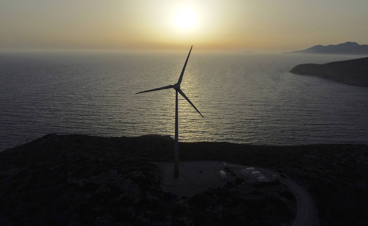 The sun sets behind a wind turbine on the Aegean Sea island of Tilos, southeastern Greece, Monday, ...