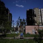 
              A resident sits outside buildings damaged by shelling in Irpin, outskirts of Kyiv, Ukraine, Tuesday, May 24, 2022. (AP Photo/Natacha Pisarenko)
            