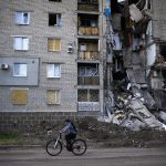 
              A woman rides a bicycle past a residential building heavily damaged in a Russian bombing in Bakhmut, eastern Ukraine, Tuesday, May 24, 2022. The town of Bakhmut has been coming under increasing artillery strikes, particularly over the last week, as Russian forces try to press forward to encircle the city of Sieverodonetsk to the northeast. (AP Photo/Francisco Seco)
            