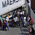 
              People try to cross through shipping containers placed by authorities in an attempt to foil a planned rally, in Lahore, Pakistan, Wednesday, May 25, 2022. Pakistani authorities blocked off all major roads into the capital Islamabad on Wednesday, after a defiant former Prime Minister Imran Khan said he would march with demonstrators to the city center for a rally he hopes will bring down the government and force early elections.(AP Photo/K.M. Chaudary)
            