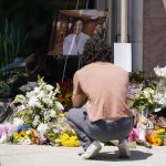 
              Gabe Kipers, a neighbor of Dr. John Cheng, kneels at a memorial for him outside his office building on Tuesday, May 17, 2022, in Aliso Viejo, Calif. Cheng, 52, was killed in Sunday's shooting at Geneva Presbyterian Church. (AP Photo/Ashley Landis)
            
