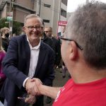 
              Labor Party leader Anthony Albanese, center, shakes hands with a voter he and his partner Jodie Haydon, left, arrive a polling place to cast their ballots in Sydney, Australia, Saturday, May 21, 2022. Australians go to the polls following a six-week election campaign that has focused on pandemic-fueled inflation, climate change and fears of a Chinese military outpost being established less than 1,200 miles off Australia's shore. (AP Photo/Rick Rycroft)
            