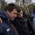 
              Yura Nechyporenko, 15, hugs his uncle Andriy Nechyporenko next to the grave of his father Ruslan Nechyporenko at the cemetery in Bucha, on the outskirts of Kyiv, Ukraine, on Monday, April 25, 2022. The teen survived an attempted killing by Russian soldiers while his father was killed, and now his family seeks justice. (AP Photo/Emilio Morenatti)
            