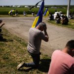 
              Mourners kneel as they await the coffin of Volodymyr Losev, 38, to pass by during his funeral in Zorya Truda, Odesa region, Ukraine, Monday, May 16, 2022. Volodymyr Losev, a Ukrainian volunteer soldier, was killed May 7 when the military vehicle he was driving ran over a mine in eastern Ukraine. (AP Photo/Francisco Seco)
            