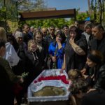 
              Mourners pay their respects to Volodymyr Losev, 38, during his funeral in Zorya Truda, Odesa region, Ukraine, Monday, May 16, 2022. Volodymyr Losev, a Ukrainian volunteer soldier, was killed May 7 when the military vehicle he was driving ran over a mine in eastern Ukraine. (AP Photo/Francisco Seco)
            