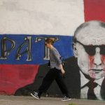 
              A woman passes by a mural depicting the Russian President Vladimir Putin that reads: ''Brother'' vandalized with paint, in Belgrade, Serbia, Saturday, May 7, 2022. Despite having to pay a big price Serbia for not introducing sanctions to Russia, Serbia will not do it , Serbian President Vucic said, but despite that the country will stay on its path toward the EU. (AP Photo/Darko Vojinovic)
            
