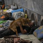 
              A man pets a dog in the city subway of Kharkiv, in eastern Ukraine, on Thursday, May 19, 2022. Although the bombings in Kharkiv have decreased and the subway is expected to run beginning of next week, still some residents use it as a temporary bomb shelter. (AP Photo/Bernat Armangue)
            