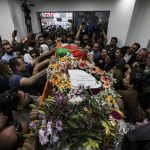 
              Palestinians surround the Palestinian flag-draped body of veteran Al-Jazeera journalist Shireen Abu Akleh, as it is brought to the news channel's office in the West Bank city of Ramallah, Wednesday, May 11, 2022. Abu Akleh, 51, was shot and killed while covering an Israeli military raid in the occupied West Bank town of Jenin early Wednesday. The broadcaster and a reporter who was wounded in the incident blamed Israeli forces. (Abbas Momani/Pool via AP)
            
