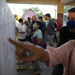 
              Residents look for their precincts on a list posted at a polling center on Monday, May 9, 2022, in Manila, Philippines. Filipinos began voting for a new president on Monday with the son of an ousted dictator and a champion of reforms and human rights as top contenders in a tenuous moment in a deeply divided Asian democracy. (AP Photo/Aaron Favila)
            