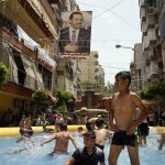 
              Children swim in an inflatable pool that supporters of former Prime Minister Saad Hariri installed to illustrate their intention to boycott parliamentary elections, in Beirut, Lebanon, Sunday, May 15, 2022. Hariri, seen in poster, suspended his participation in Lebanese politics last year and has called on supporters to boycott Sunday’s vote -- the first since Lebanon’s implosion started in October 2019. (AP Photo/Hassan Ammar)
            