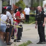 
              Police speak to bystanders while investigating after a shooting at a supermarket on Saturday, May 14, 2022, in Buffalo, N.Y.  Officials said the gunman entered the supermarket with a rifle and opened fire. Investigators believe the man may have been livestreaming the shooting and were looking into whether he had posted a manifesto online.  (AP Photo/Joshua Bessex)
            