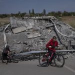 
              Teenagers on bicycles pass a bridge destroyed by shelling near Orihiv, Ukraine, Thursday, May 5, 2022. (AP Photo/Evgeniy Maloletka)
            