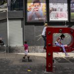 
              FILE - Children play on the letter "P" that is part of the acronym for the state-run oil company Petroleos de Venezuela S.A. (PDVSA) on the sidewalk in Caracas, Venezuela, Jan. 2, 2022. The United States government is moving to ease a few economic sanctions on Venezuela, which sits atop the world’s largest oil reserves and where about three quarters of its population live on less than $1.90 a day and lack access to clean, running water and electricity. (AP Photo/Matias Delacroix, File)
            